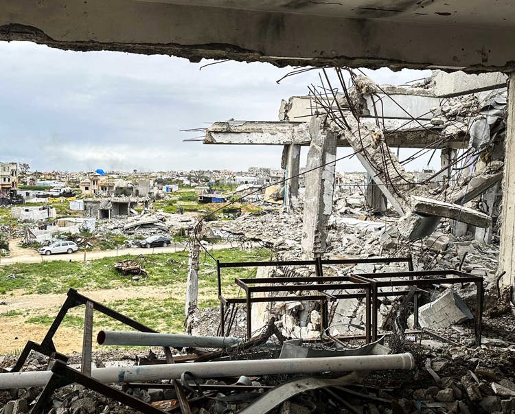 From the opening of a destroyed building, rubble is seen littering the Gaza Strip land